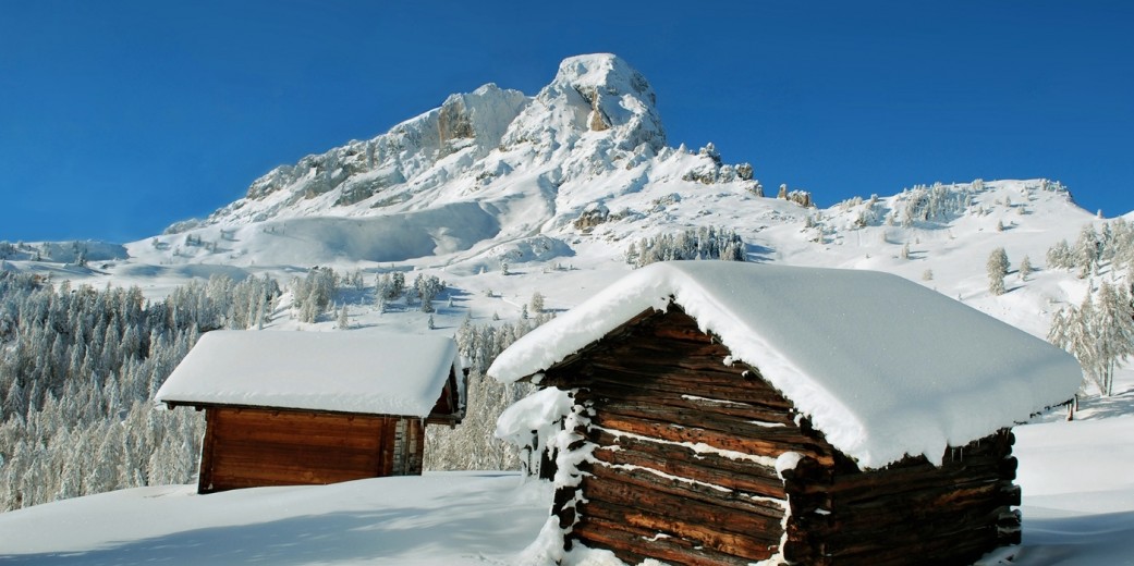 Snow-blanketed Alpine huts at the foot of the Pütia/Peitlerkofel