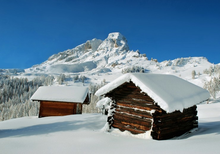 Snow-blanketed Alpine huts at the foot of the Pütia/Peitlerkofel